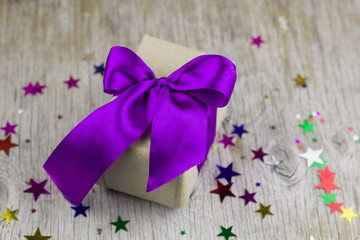  gift box with violet satin ribbon on the wooden table