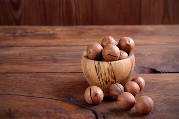 Wall Mural - Macadamia nuts in a bowl on a wooden background.