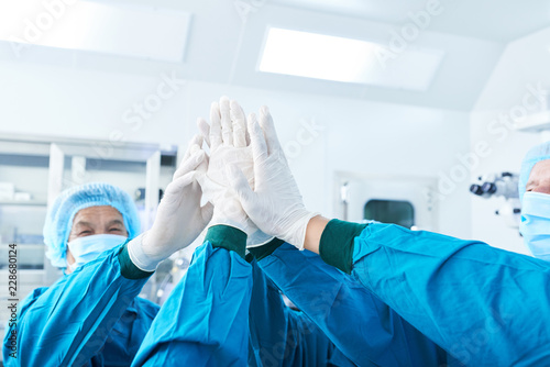 Fotografía Crop surgeons in gloves giving high five to each other before performing surgery