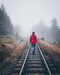Wanderer läuft in roter Jacke über Schienen im Harz