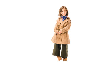 Wall Mural - beautiful little child in trench coat looking at camera isolated on white