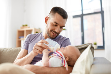 family, parenthood and people concept - father feeding little daughter with baby formula from bottle