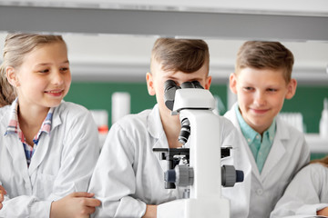 Sticker - education, science and children concept - kids or students with microscope studying biology at school laboratory