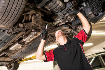 handsome mechanic based on car in auto repair shop