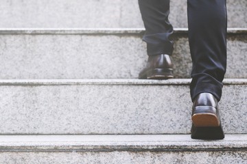 close up legs shoes of young business man one person walking stepping going up the stairs in modern 