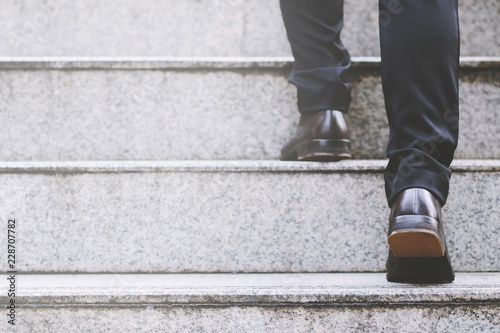 Cuadros en Lienzo Close up legs shoes of young business man One person walking stepping going up the stairs in modern city, go up, success, grow up