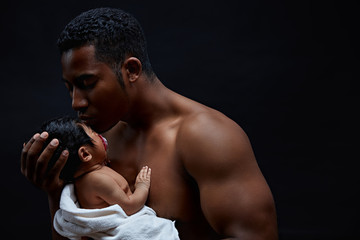 handsome black man is blessing his child. copy space. isolated on the black background. father wises the health and happiness to his infant. close up side view photo