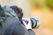 Richmond Park, London. A male photographer using a camera with a large camouflaged lens takes a photograph.