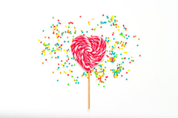 Heart Lollipop and multi coloured sweets on a gently white backg