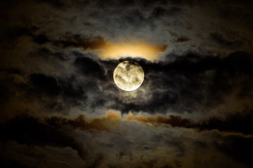 full moon ascending behind dark clouds