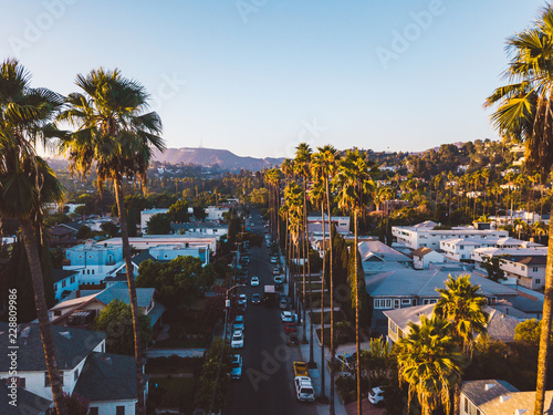 Fotografía Beverly Hills street with palm trees at sunset in Los Angeles with Hollywood sign on the horizon