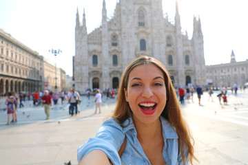 Happy young woman take selfie photo in front of Milan Cathedral. Self portrait of beautiful girl in Milan, Italy.