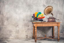 Vintage Antique Brass Gramophone Phonograph Turntable And Colorful Vinyl Discs In Aged Special Holder Suitcase On Oak Wooden Table Front Concrete Wall Background. Retro Old Style Filtered Photo