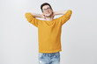 © Cookie Studio - Work can wait. Portrait of carefree relaxed and lazy handsome young european man in warm sweater laying back holding hands behind neck and smiling enjoying weekends over gray background