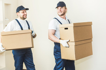 Delivery man loading cardboard boxes for moving to an apartment. professional worker of transportation, male loaders in overalls