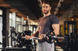 © djile - Handsome man doing biceps lifting in a gym