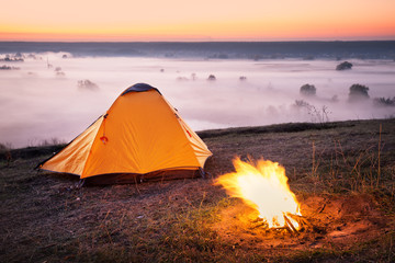 Wall Mural - orange tent on foggy morning on hill above rive