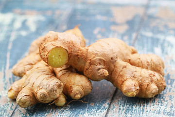 closeup of fresh root of ginger on blue rustic wooden surface