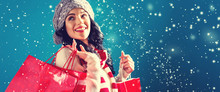 Happy Young Woman Holding Shopping Bags In A Snowy Night