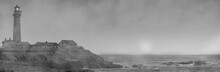 Black And White Of The Fog Rolling In On A Lighthouse With The Sun Still Up ,on The California Coastline