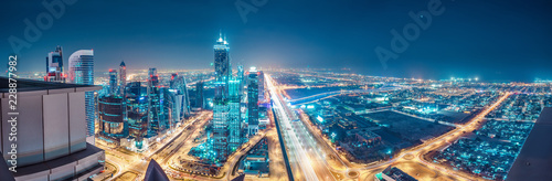 Obraz Dibond Spektakularna miejska panorama z kolorowymi iluminacjami miasta. Widok z lotu ptaka na autostradach i drapaczach chmur w Dubaju, Zjednoczone Emiraty Arabskie.