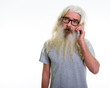 © Ranta Images - Studio shot of senior bearded man thinking while talking on mobi