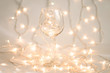 © Valentina - Wine glass with holiday lights inside on white background