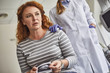 Disappointing results. Waist up portrait of middle-aged woman with sonography picture in hands. Supportive doctor in white lab coat and sterile gloves touching lady shoulder