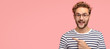 Cheerful curly man with bristle, points left, wears casual clothes and spectacles, has satisfied expression, shows free space for your slogan, promotional content or advertisemet. Look aside there