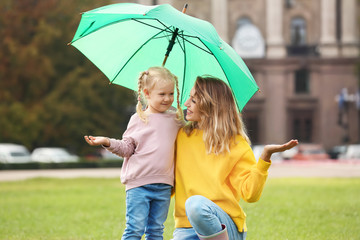 Wall Mural - Happy mother and daughter with umbrella in park