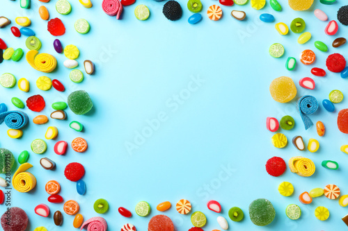 Plakat Flat lay composition with delicious colorful candies and space for text on color background