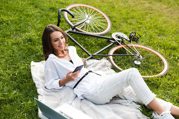 Poster - Smiling young woman bicyclist spending time at the park