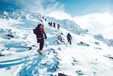 Fototapeta  - A group of climbers ascending a mountain in winter