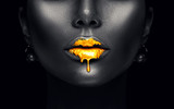 Fototapeta  - Gold paint drips from the sexy lips, golden liquid drops on beautiful model girl's mouth, creative abstract makeup. Beauty woman face isolated on black