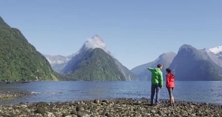 Wall Mural - Milford Sound tourist couple hiking in New Zealand enjoying iconic view of Mitre Peak, Fjord and famous tourist destination in Fiordland National Park,.