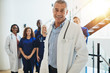 © Flamingo Images - Smiling mature doctor standing in a hospital with his staff