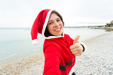 Christmas and holidays concept - Beautiful woman in Santa Claus costume taking selfies over nature background