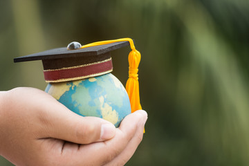 Wall Mural - education world knowledge ideas. graduation cap on businessman holding earth globe model in hands. c