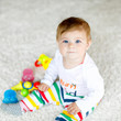 © Irina Schmidt - Adorable baby girl playing with educational toys in nursery. Happy healthy child having fun with colorful different toys at home. Baby development and first steps, learning to play and to grab.