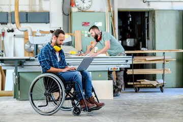 Wall Mural - worker in wheelchair in a carpenter's workshop with his colleagu