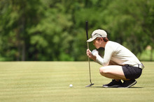 Woman Golfer Check Line For Putting Golf Ball On Green Grass