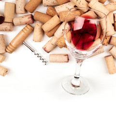 Wall Mural - Glass of red wine with corks and corkscrew on a white background with copy space, top shot