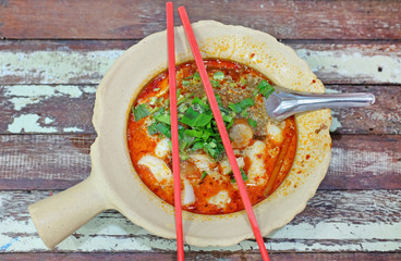 Canvas Print - Spicy fish noodle in the bowl with chopsticks and spoon on wood table.