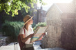 Girl traveler is using city map at town street. Woman tourist is searching direction, exploring locations, walking in magic light. Concept of travel, vacation, female tourism, adventure, trip, journey