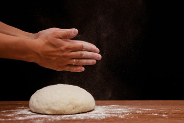 a lump of dough lie on a wooden table on a black background