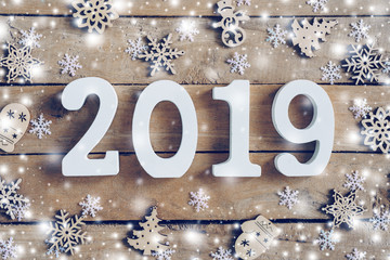 Wooden numbers forming the number 2019, For the new year and white snow with snowflakes on rustic wooden background.