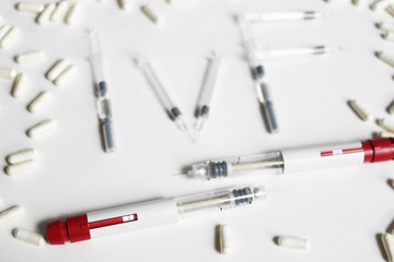 In Vitro Fertilization injection pen. IVF treatment drugs, syringes, needles and pills. Stims and pio shots. Medication for infertility treatment on white background.  IVF spelled with syringes. 