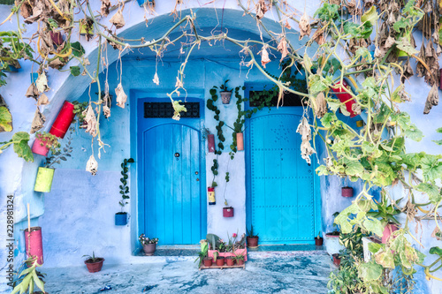 Fotografie, Obraz Typical blue facade with ancient doors decorated with pots in Chefchaouen, Moroc