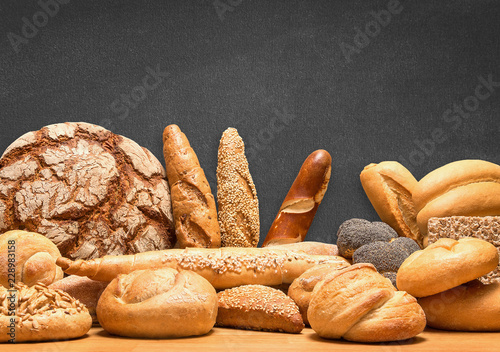 Fotomural Reiche Auswahl an Brot und Gebäcksortiment mit Tafel im Hintergrund für eigene B