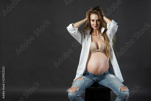 Beautiful smiling pregnant young blond woman, wearing ripped ...
